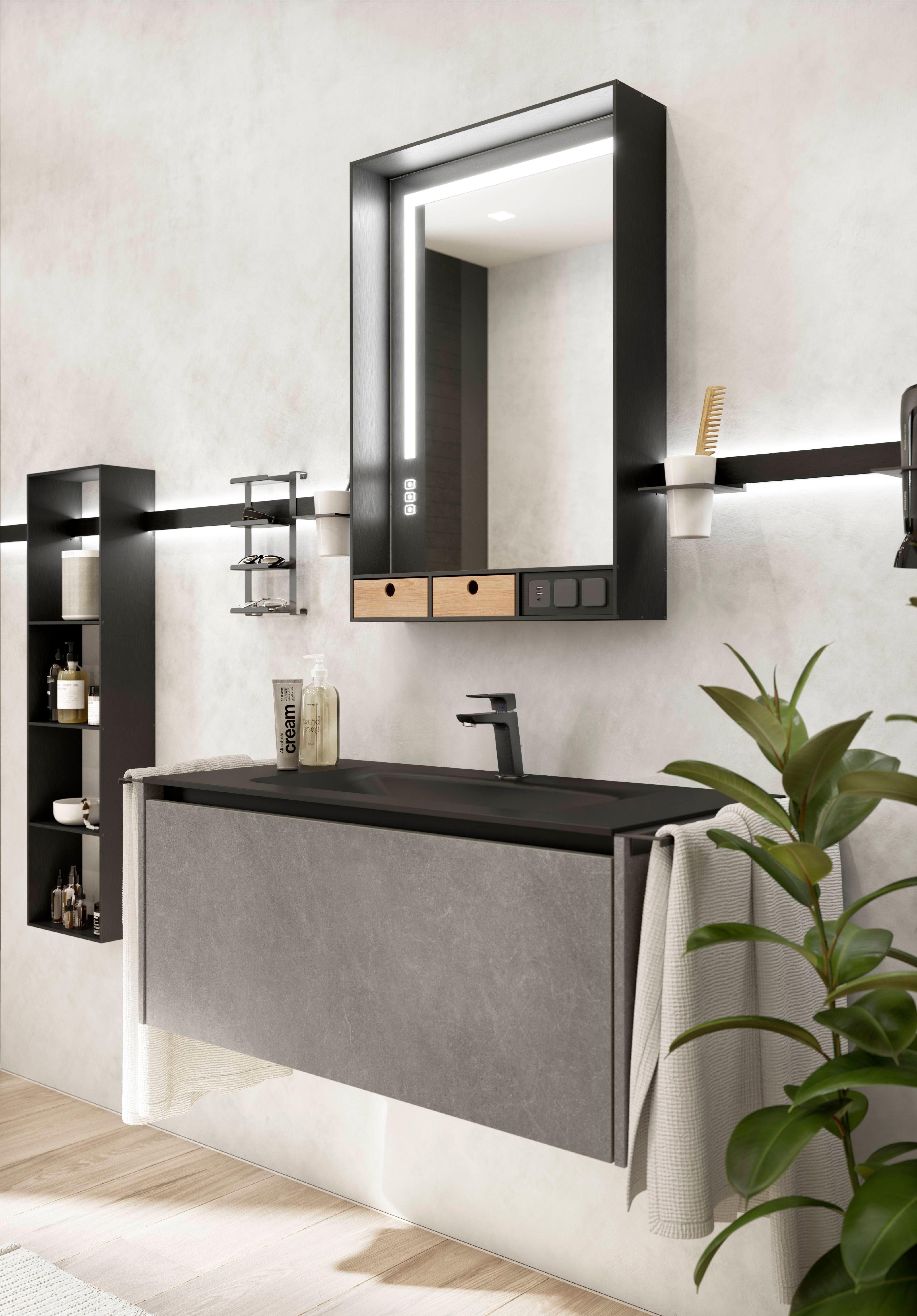 Badezimmer mit grauer Betonoptik, schwarzem Waschbecken und integrierter Beleuchtung im Spiegel.