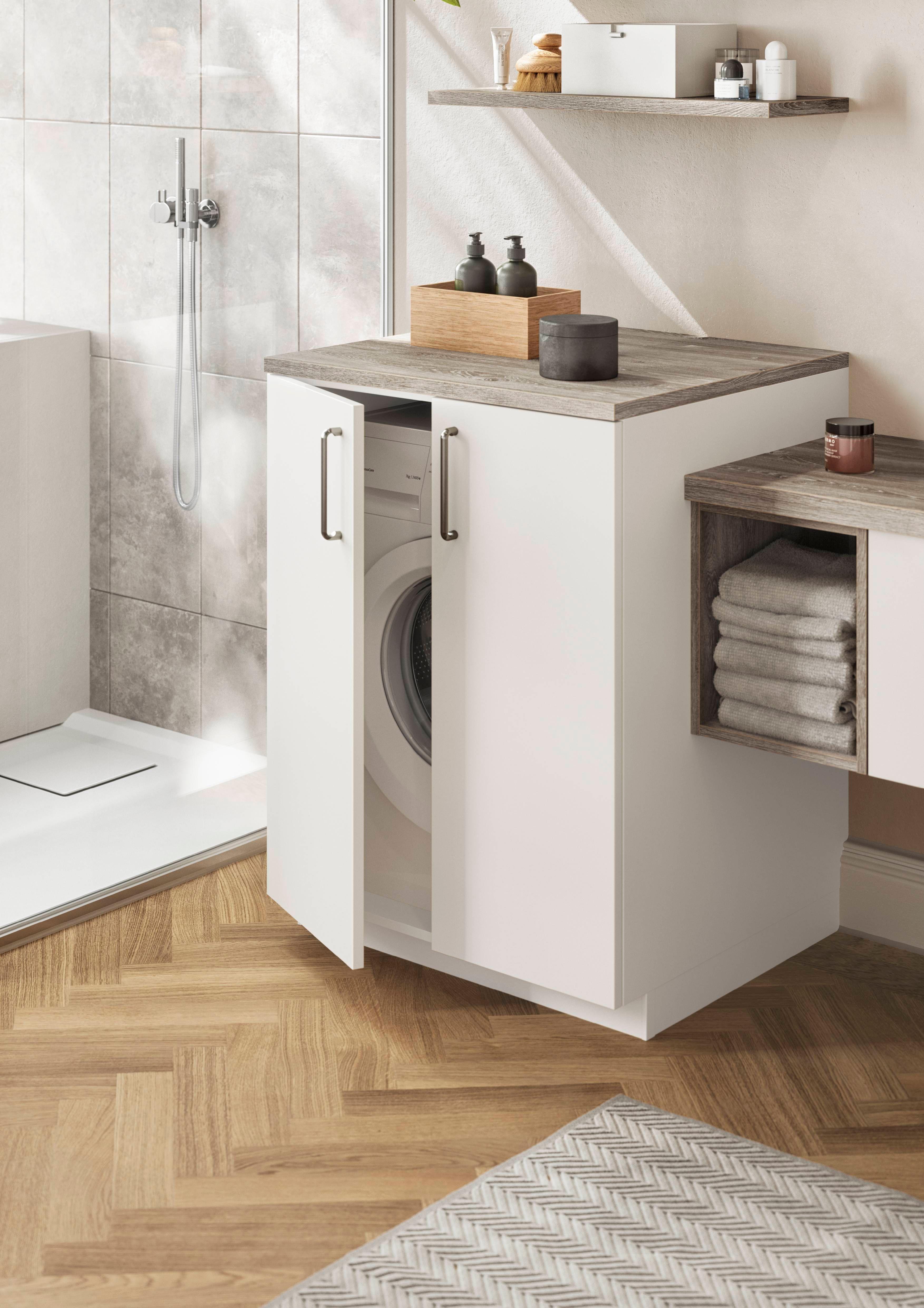 Waschmaschine im weißen Unterschrank mit Holzarbeitsplatte in einem modernen Badezimmer integriert.