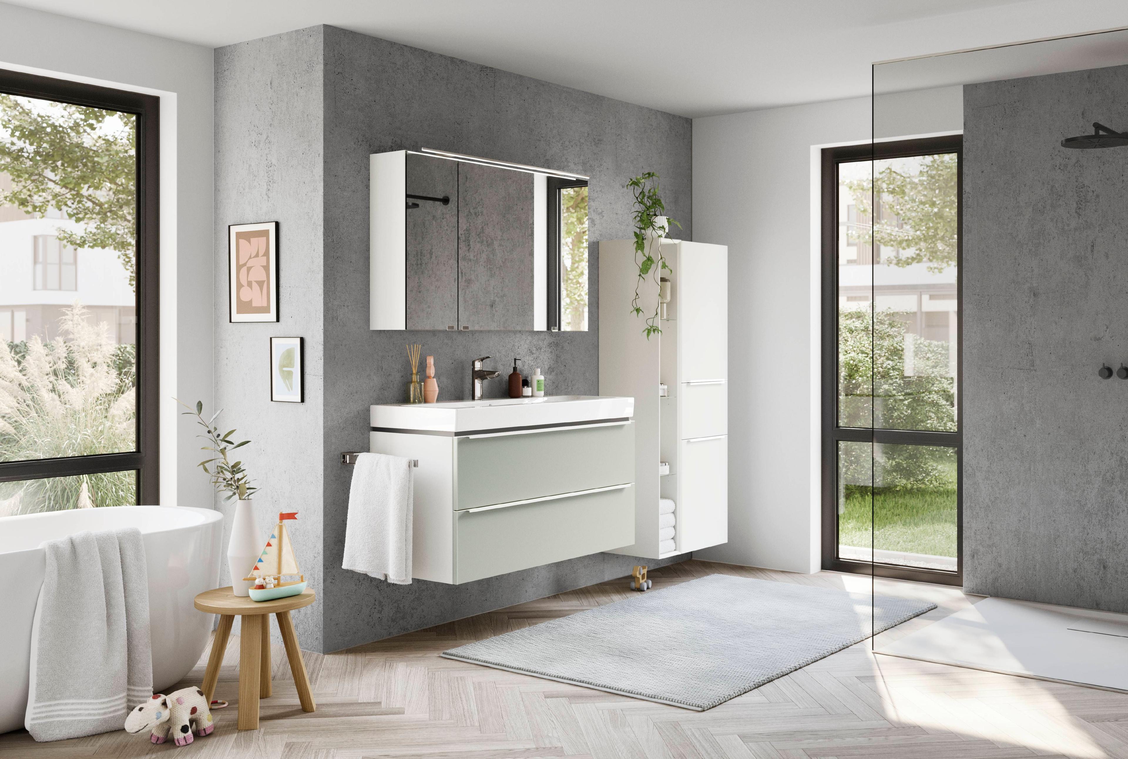 Modern eingerichtetes Badezimmer mit hellgrüner Waschtischkombination, Spiegelschrank, Hochschrank und freistehender Badewanne in freundlichem, lichtdurchflutetem Ambiente.