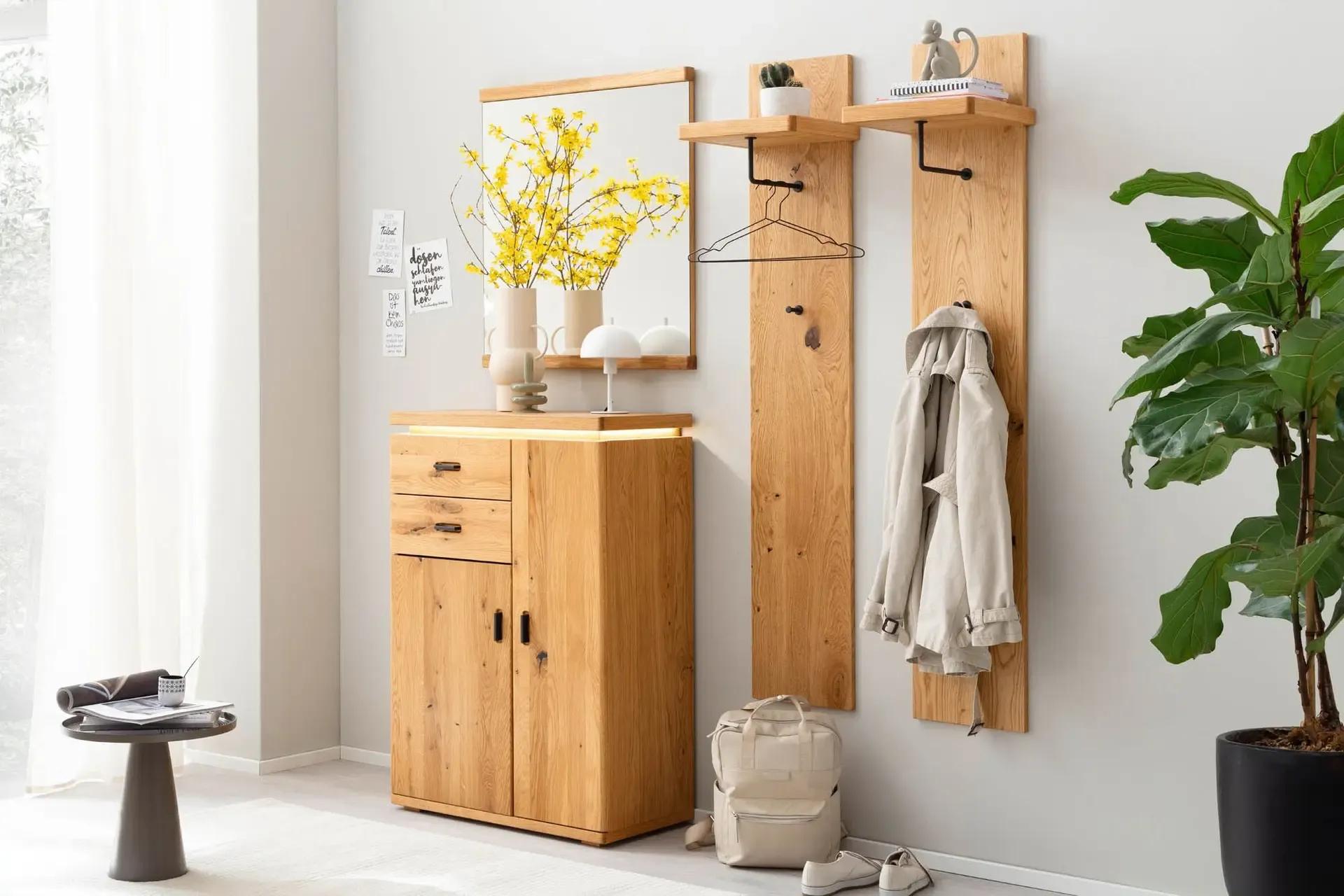 Moderne Garderobenkombination aus massiver Eiche mit Spiegel, Wandpaneelen, Haken und Kommode in einem hell eingerichteten Flur.