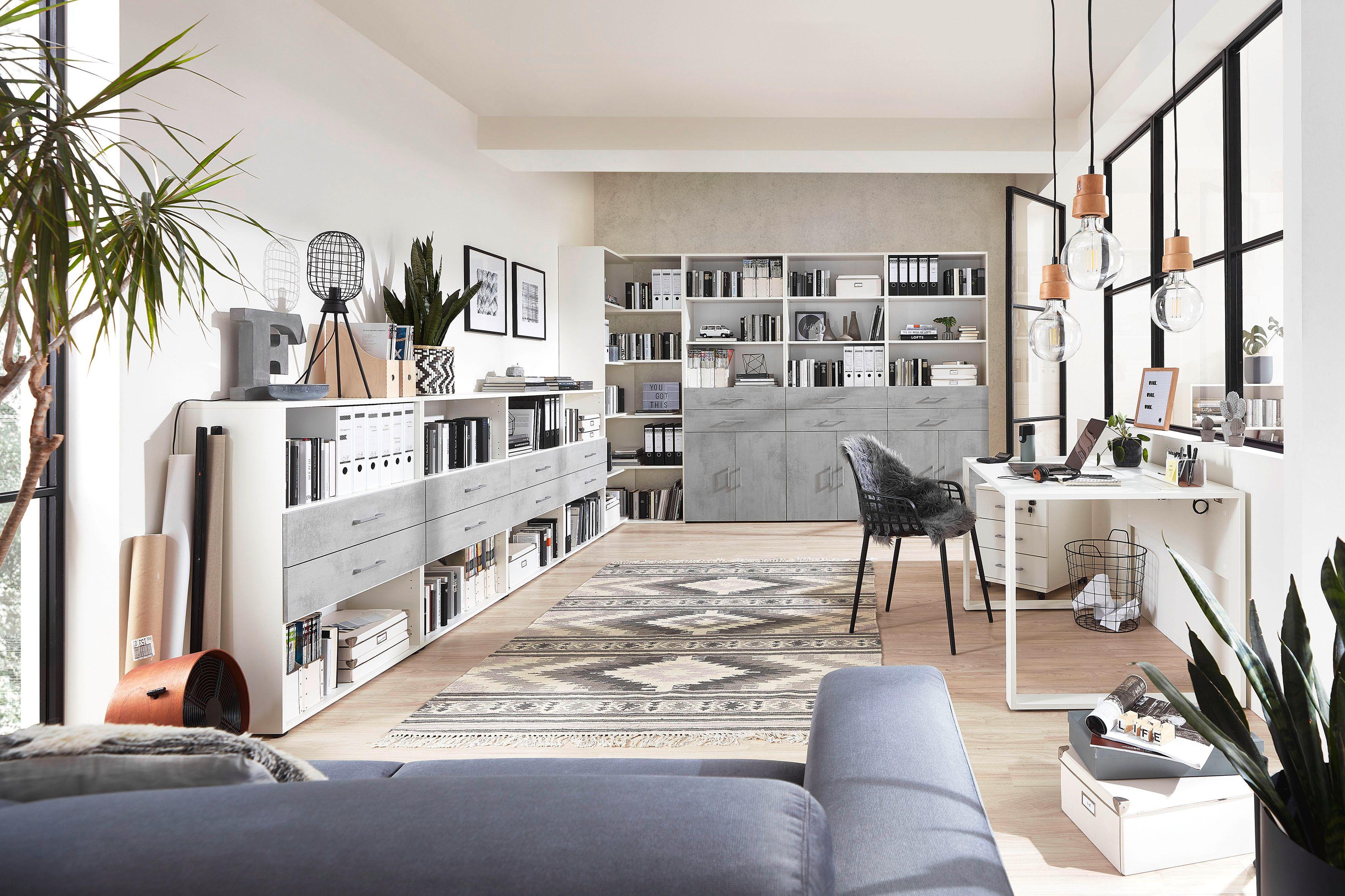 Helles, offenes Büro mit Betonoptik-Fronten, weißen Korpussen und gemütlicher Sofaecke.