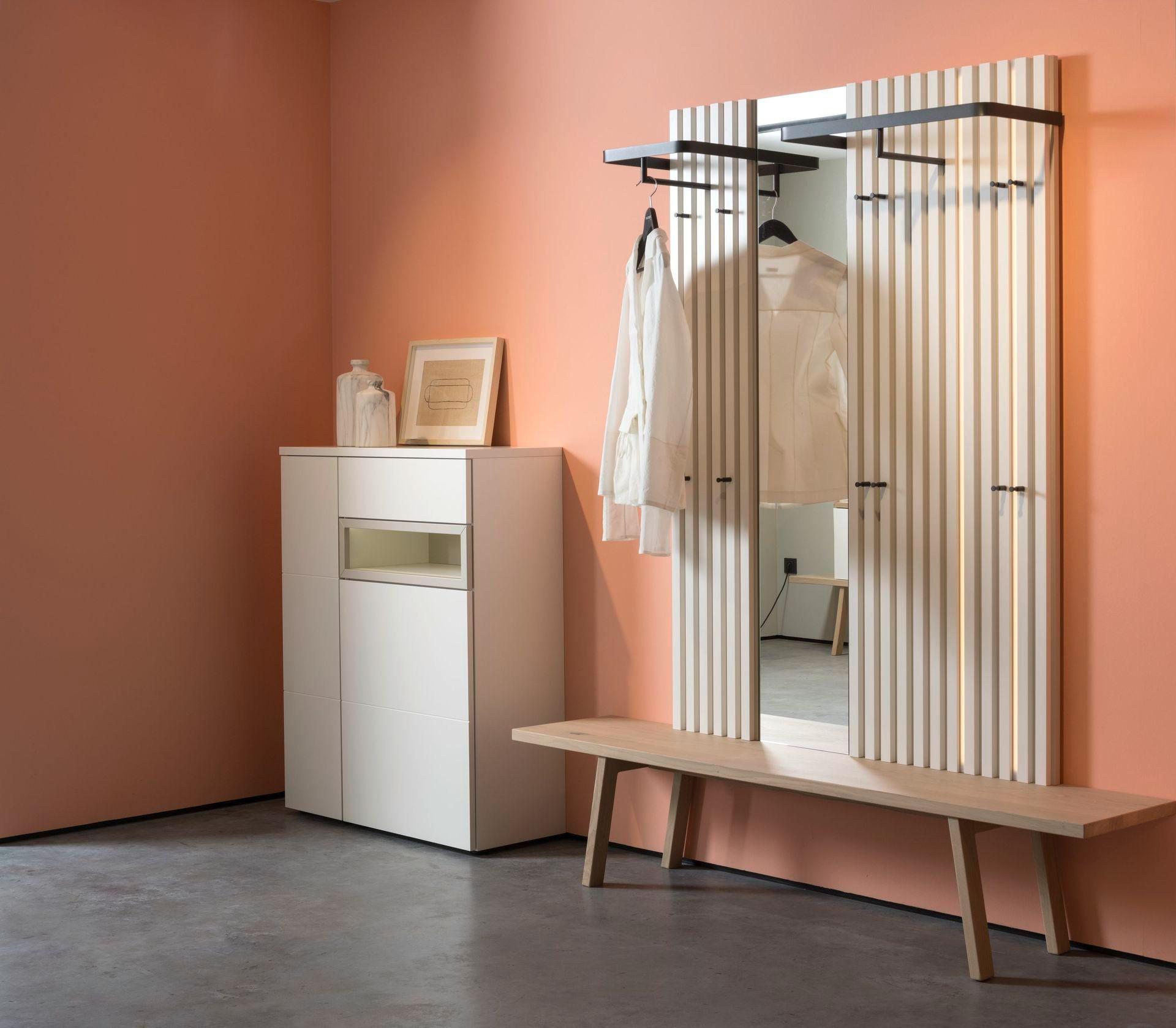 Garderobe mit vertikalen Leisten, großem Spiegel und minimalistischer Kommode in Weiß