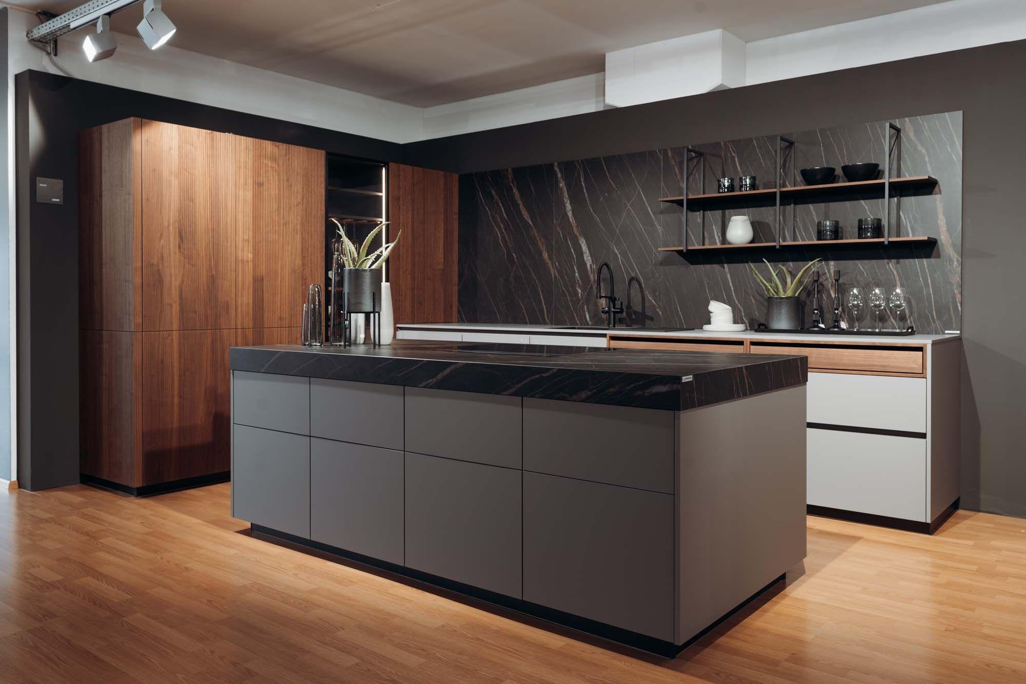 Moderne Designer-Küche mit grauer Kochinsel, schwarzer Marmorarbeitsplatte, Holzfronten, dunkler Naturstein-Rückwand und schwimmenden Regalen auf Parkettboden. Moderne Designer-Küche mit grauer Kochinsel, schwarzer Marmorarbeitsplatte, Holzfronten, dunkler Naturstein-Rückwand und schwimmenden Regalen auf Parkettboden.