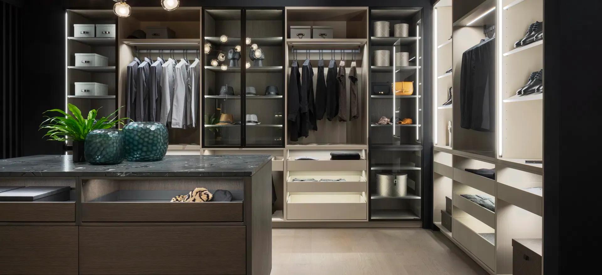 Modernes Ankleidezimmer mit offener Schranklösung, indirekter Beleuchtung und zentraler Kommode mit dunkler Steinplatte Modernes Ankleidezimmer mit offener Schranklösung, indirekter Beleuchtung und zentraler Kommode mit dunkler Steinplatte