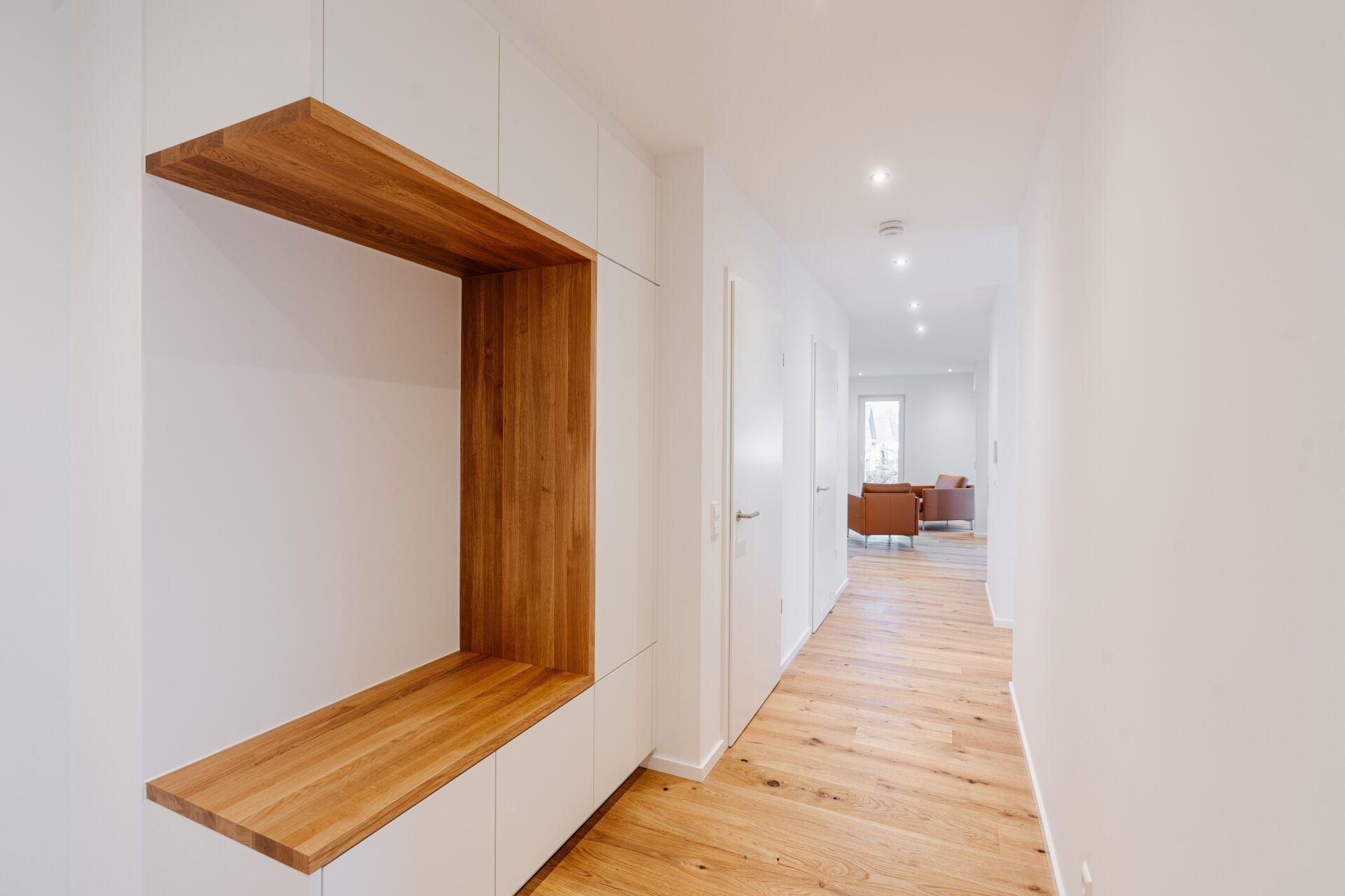 Moderne Einbaulösung im Flur mit integrierter Sitzbank und Eichenholzverkleidung.