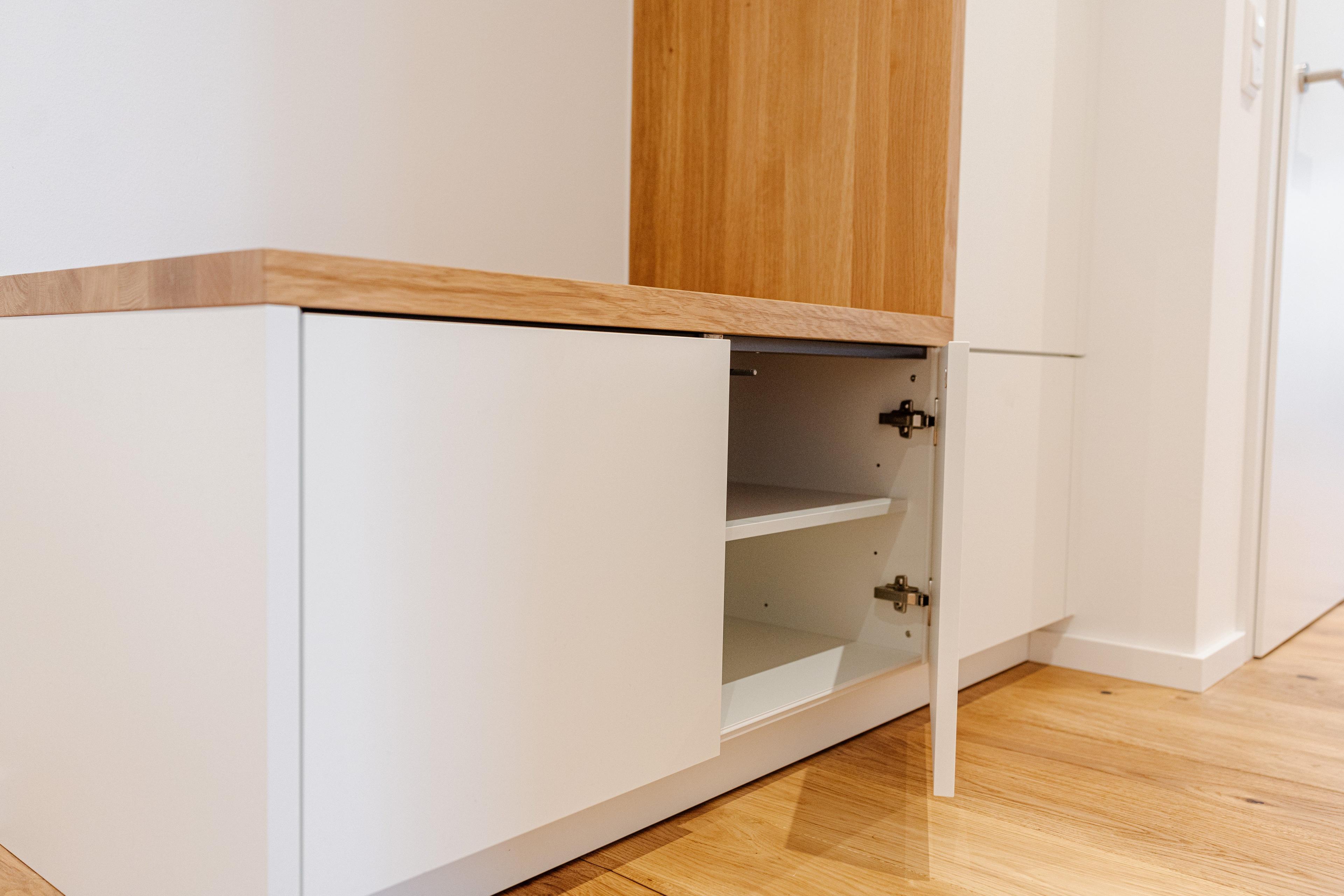 Detailansicht des unteren Schranks mit geöffneter Tür und sichtbarem Innenfach.