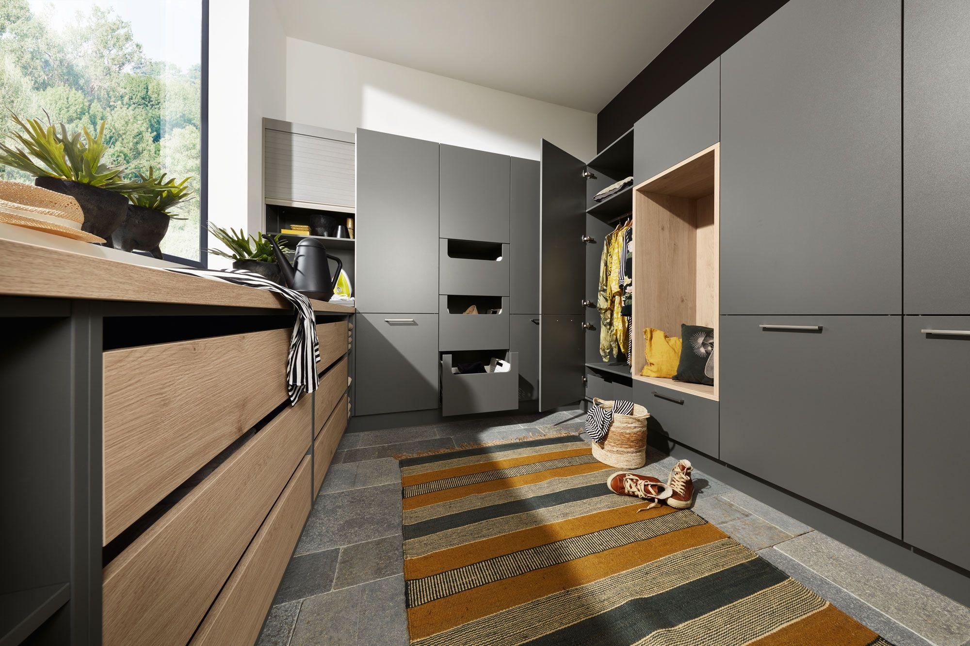 Moderner Hauswirtschaftsraum mit anthrazitfarbenen und Holz-Schränken, ausziehbaren Wäschekörben und integriertem Garderobenschrank mit viel Tageslicht.