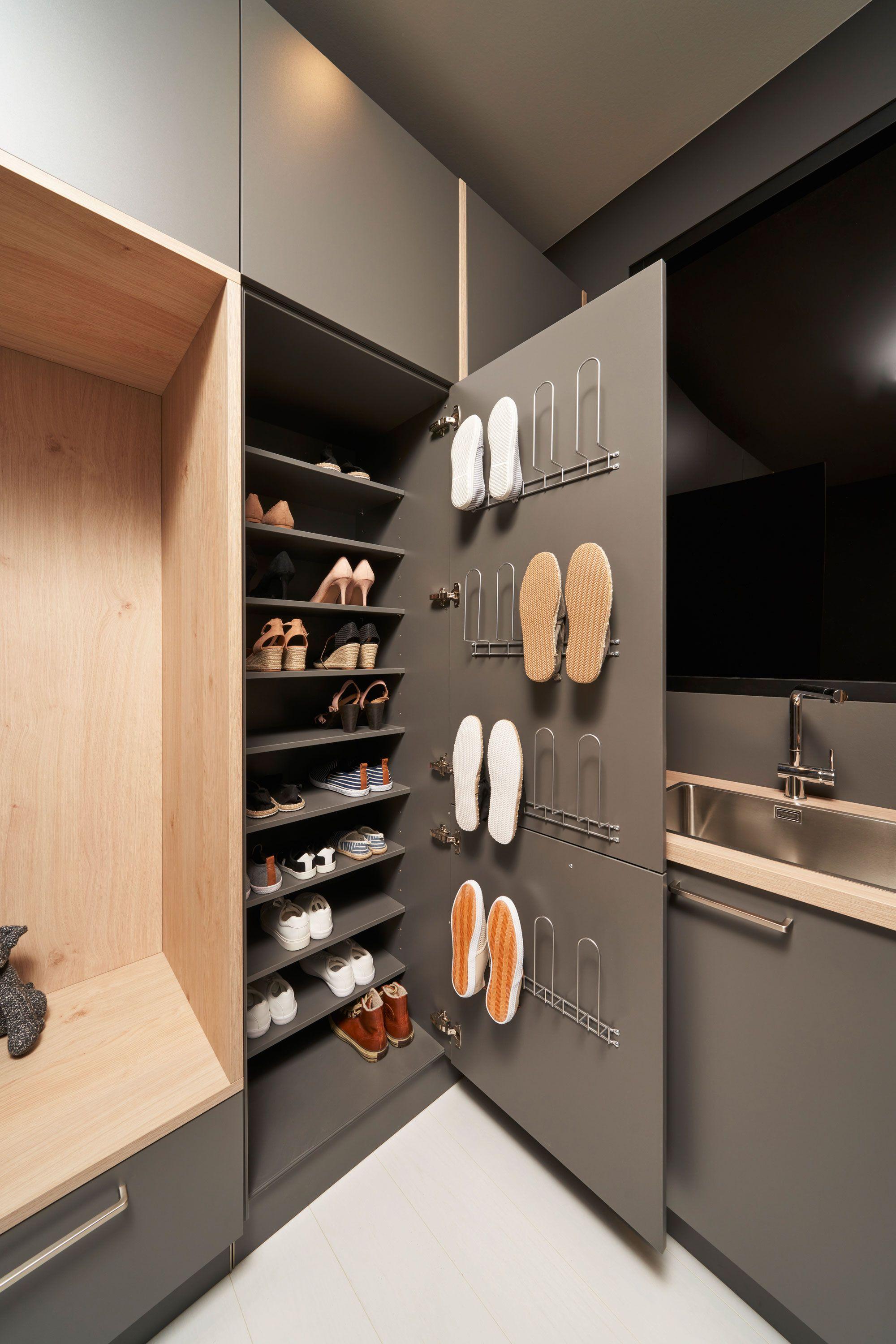 Hauswirtschaftsraum mit anthrazitfarbenen Schränken, ausziehbaren Schuhregalen und cleveren Schuhhalterungen an den Türinnenseiten.