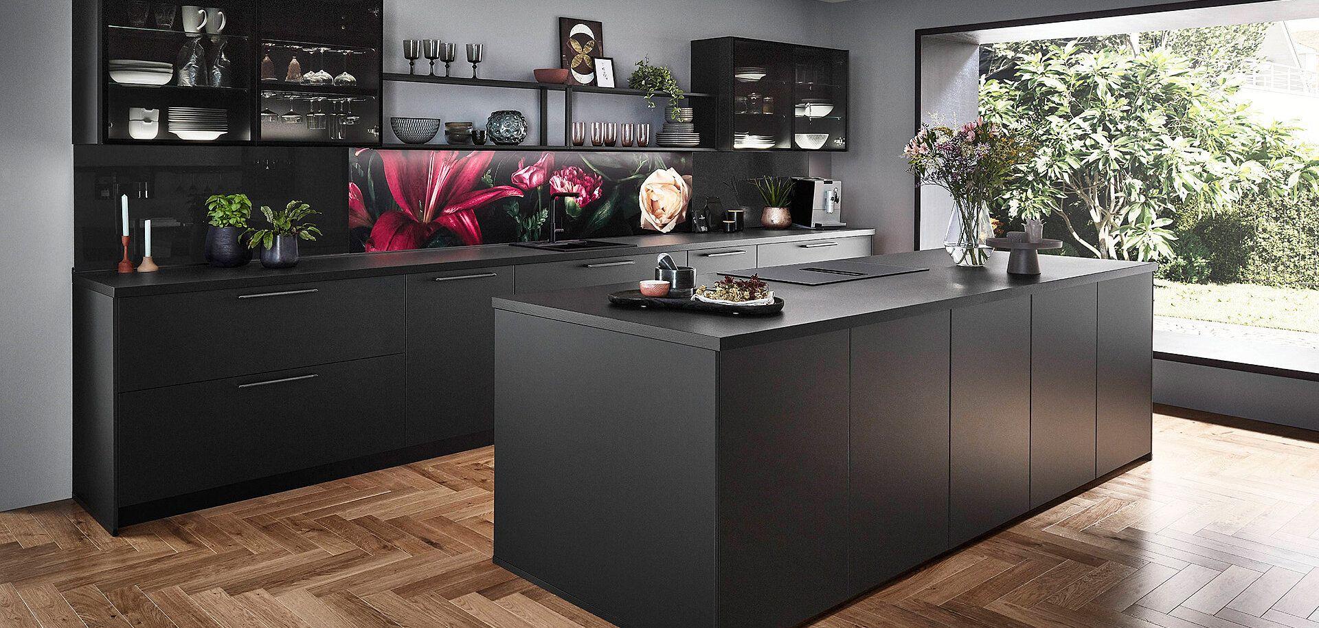 Moderne schwarze Küche mit Insel, eleganter Rückwandgestaltung und Blick auf den Garten.