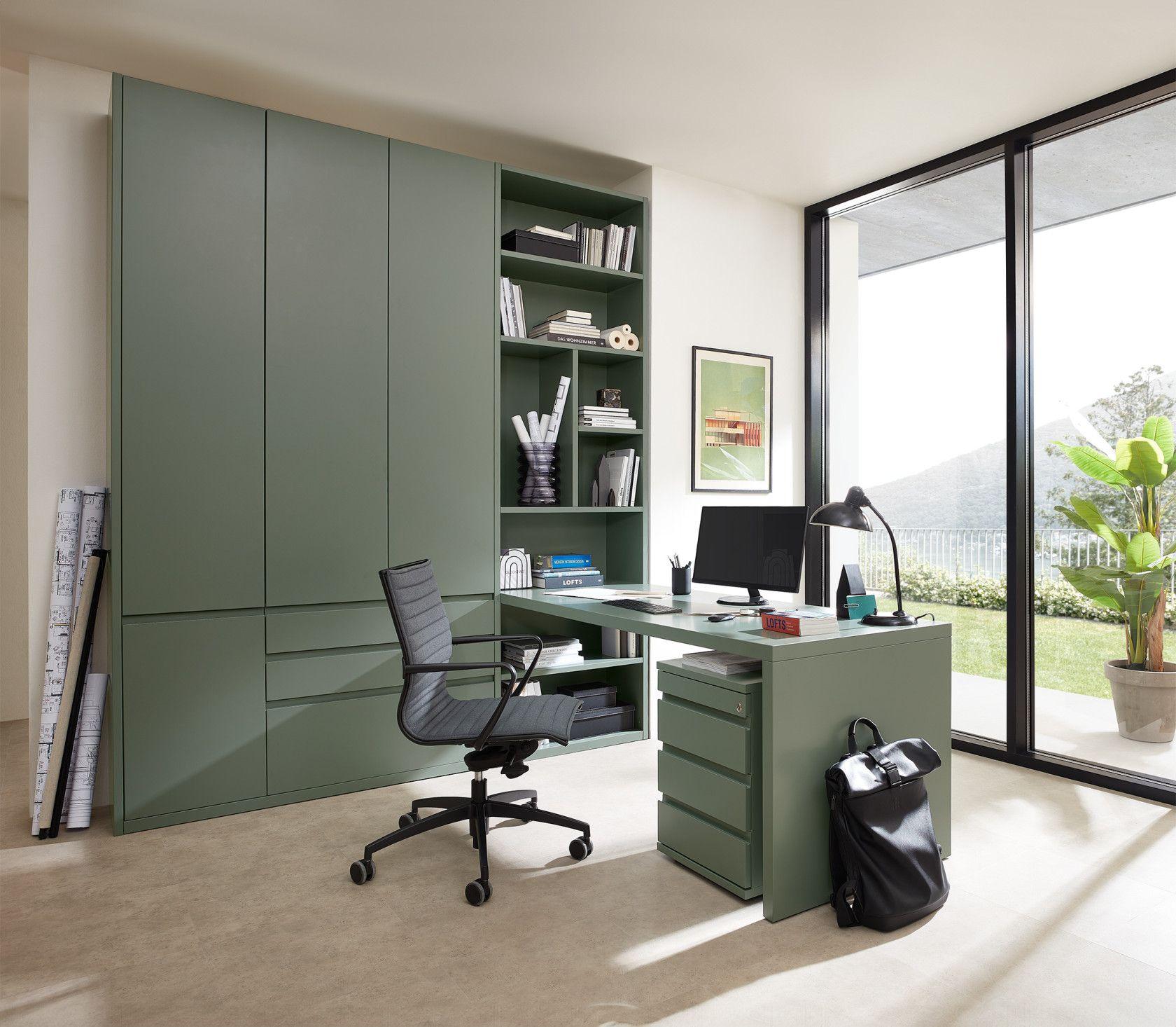 Modernes Home-Office in Olivgrün mit integriertem Schreibtisch, Bücherregal und schwarzem Bürostuhl, große Terrassentür mit Gartenblick.