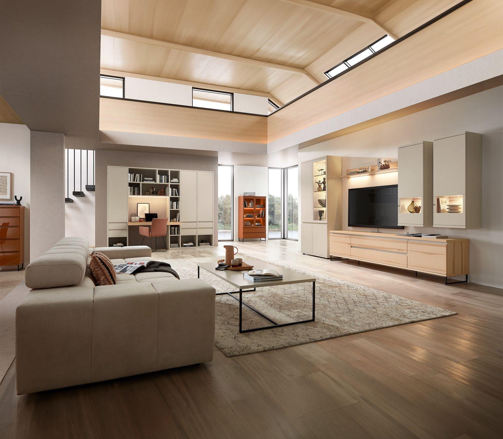 Modern eingerichtetes Wohnzimmer mit heller Wohnwand, Sofa, Couchtisch und integriertem Arbeitsplatz – großzügiger, lichtdurchfluteter Raum mit Holzdecke. Modern eingerichtetes Wohnzimmer mit heller Wohnwand, Sofa, Couchtisch und integriertem Arbeitsplatz – großzügiger, lichtdurchfluteter Raum mit Holzdecke.