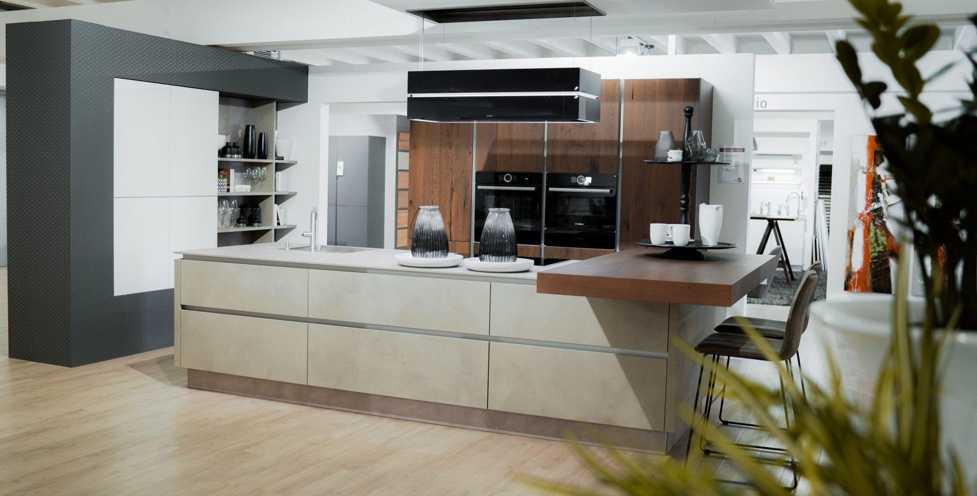 Moderne Küche mit beiger Kochinsel, Holzschränken und eingebauten schwarzen Geräten in offener Wohnraumgestaltung.