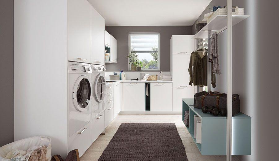 Heller Hauswirtschaftsraum in Weiß mit offenen Regalsystemen, nebeneinander angeordneten Haushaltsgeräten und Garderobenlösung.