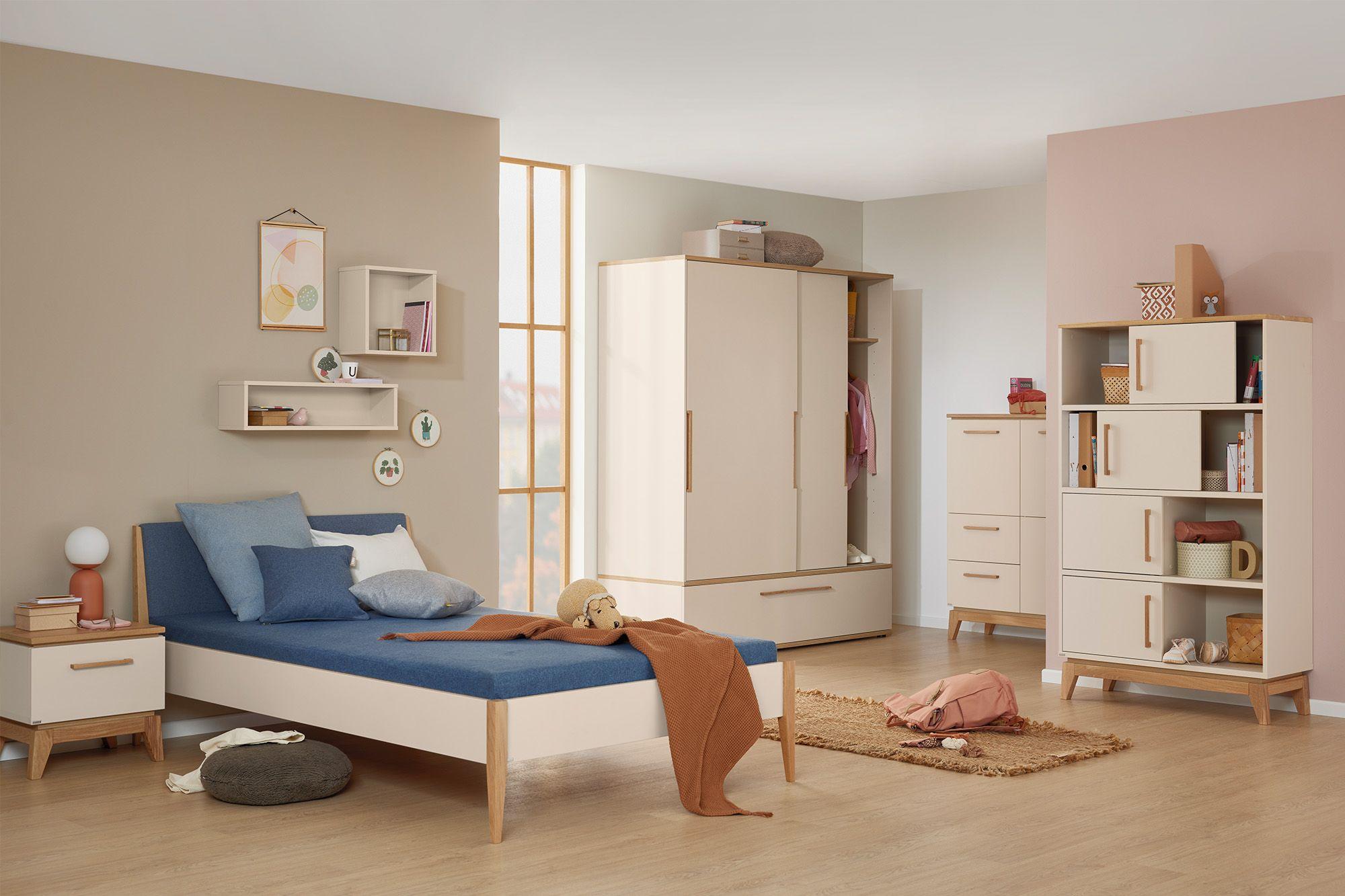 Freundlich gestaltetes Kinder- oder Jugendzimmer mit Bett, Schrankwand, Regalen und Nachttisch in Creme-Holz-Optik – kombiniert mit warmen Wandfarben und liebevollen Dekoelementen.