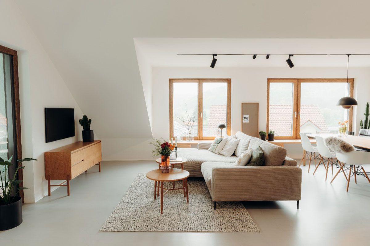 Modern, helles Wohnzimmer im skandinavischen Stil mit beiger Eckcouch, Holzmöbeln und großen Fenstern in offener Raumaufteilung. Modern, helles Wohnzimmer im skandinavischen Stil mit beiger Eckcouch, Holzmöbeln und großen Fenstern in offener Raumaufteilung.