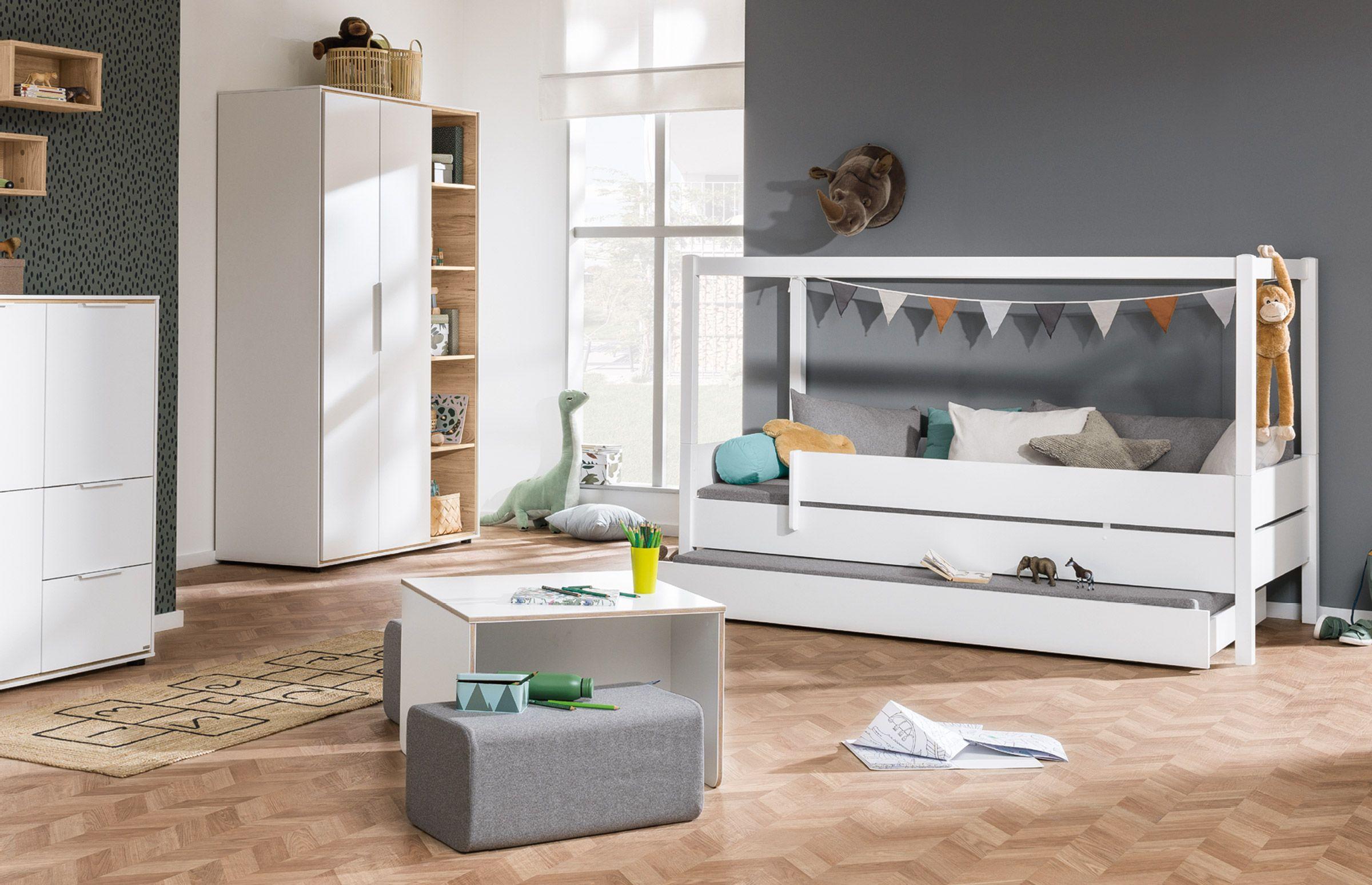 Modernes Kinderzimmer mit Hausbett in Weiß, Stauraumbett, Schrank mit offenen Fächern und Spieltisch – dekoriert mit tierischen Akzenten und bunten Wimpeln.