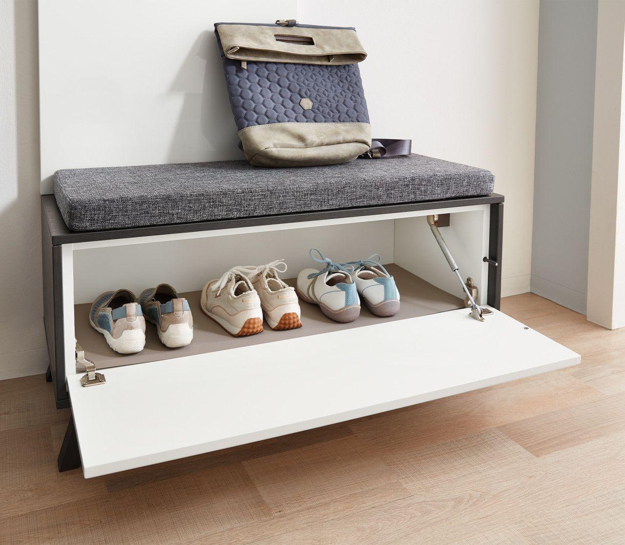 Detailaufnahme der Dielensitzbank mit aufgeklapptem Schuhfach und darauf liegendem Rucksack.