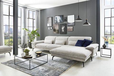 Hellgraue Eckcouch mit Chaiselongue und schwarzen Metallfüßen in modernem Loft mit Panoramafenstern.