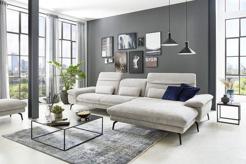 Hellgraue Eckcouch mit Chaiselongue und schwarzen Metallfüßen in modernem Loft mit Panoramafenstern.