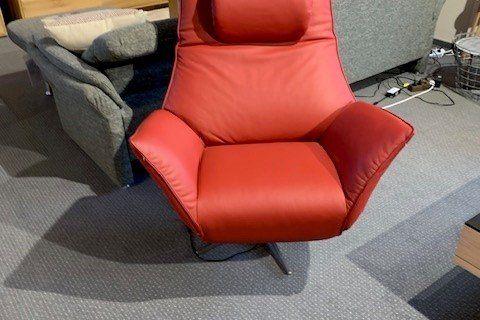 Roter Leder-Relaxsessel mit hoher Rückenlehne auf Drehgestell in Möbelhaus-Ausstellung.